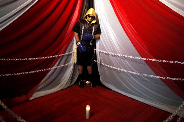 The body of boxer Christopher Rivera, who was shot to death on Sunday, is propped up in a fake boxing ring during his wake at the community recreation center within the public housing project where he lived in San Juan, Puerto Rico, Friday, Jan. 31, 2014.  Elsie Rodriguez, vice president of the Marin funeral home, explained that Rivera had asked his family that if he died, he wanted his funeral to make reference to his boxing career. (AP Photo/Ricardo Arduengo)
